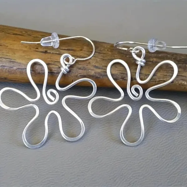 Silver wire flower earrings on wood.