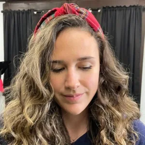 Woman with long curly hair wearing a red headband.