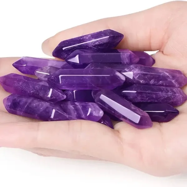 Hand holding purple amethyst crystal points.