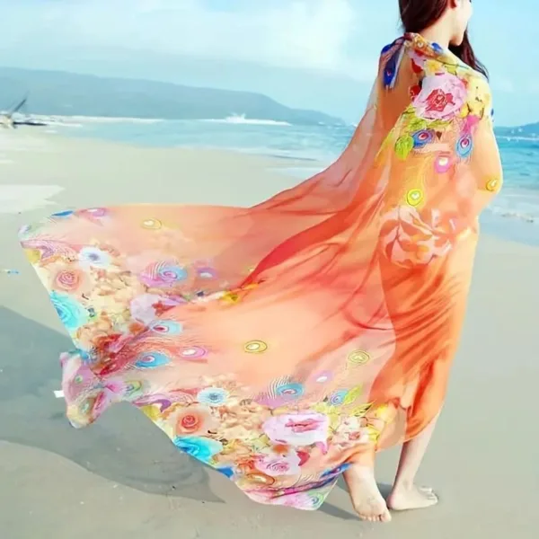 Woman wearing floral beach scarf on sand.