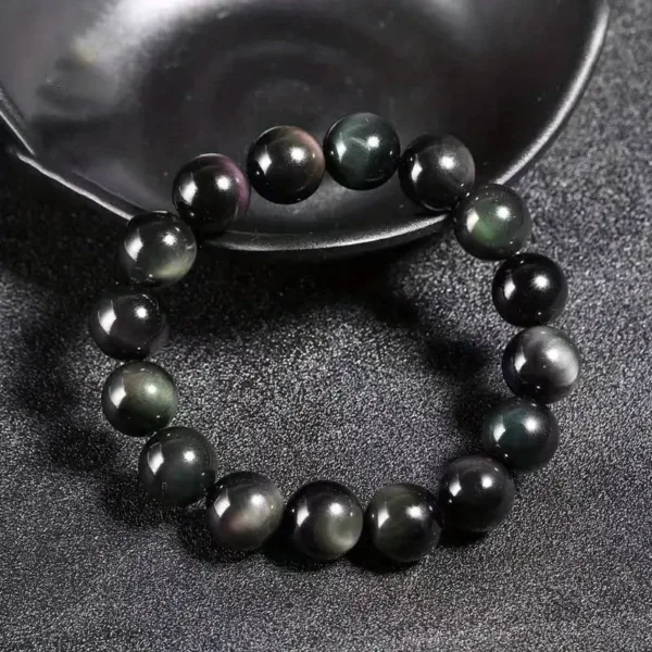 Black obsidian beaded bracelet on black background.