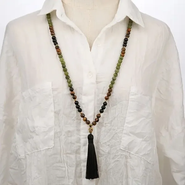 Green, black, and brown beaded necklace with tassel.