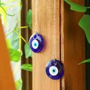 Two blue evil eye charms on chains.