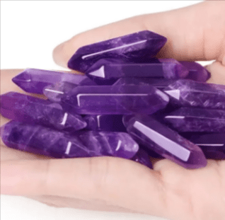 Hand holding a pile of amethyst points.