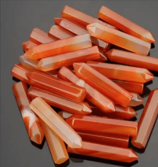 A pile of orange carnelian crystal wands.