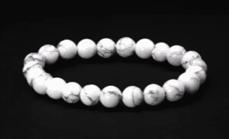 White gemstone bead bracelet on black background.