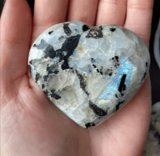 Heart-shaped moonstone crystal with black inclusions.