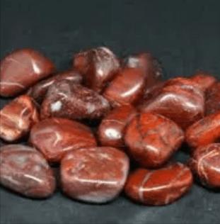 Red jasper tumbled stones on a dark background.