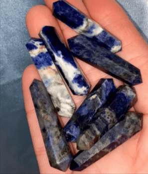 Hand holding a pile of blue sodalite points.