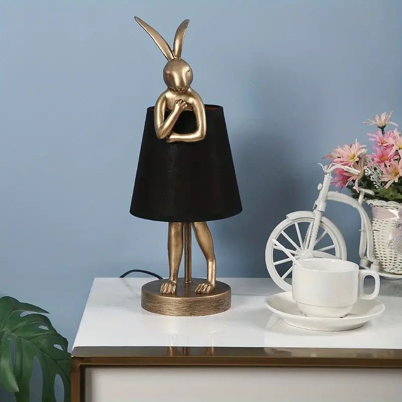 Gold rabbit table lamp with black shade.