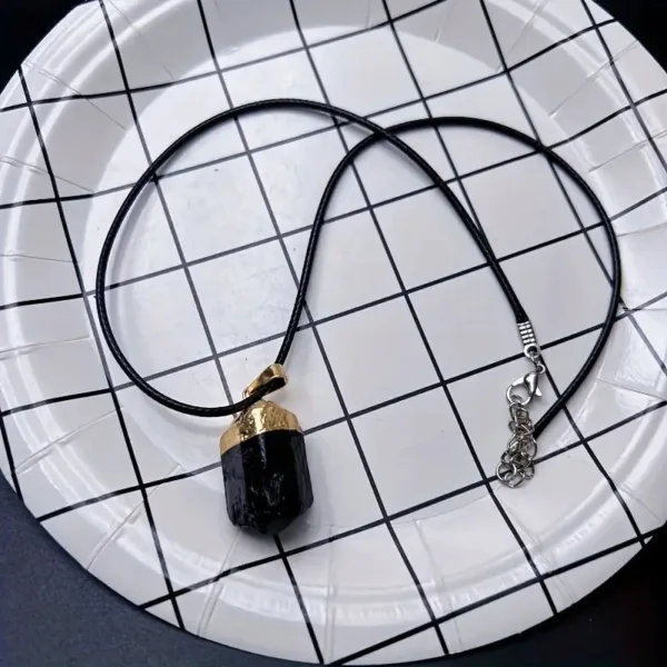 Black tourmaline pendant necklace on plate.