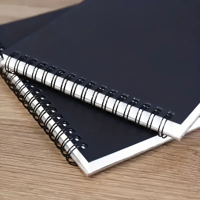 Two black spiral bound notebooks.