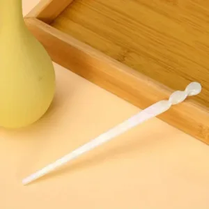 White twisted hair stick on a wooden surface.