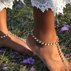 Foot with jeweled anklet on grass.