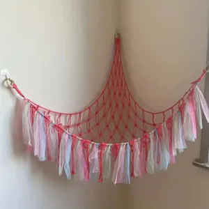 Pink and white macrame hammock hanging in corner.