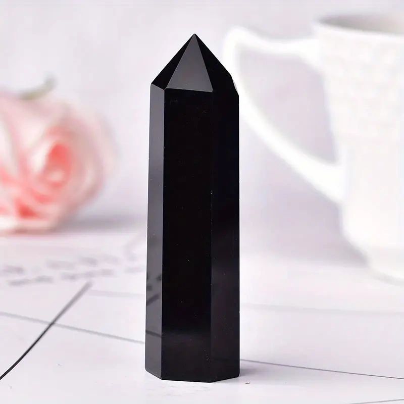 Black obsidian crystal point on table.