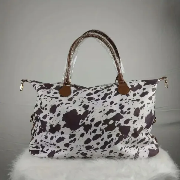 Cow print travel bag with brown handles.