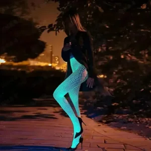 Woman in glowing fishnet tights at night.