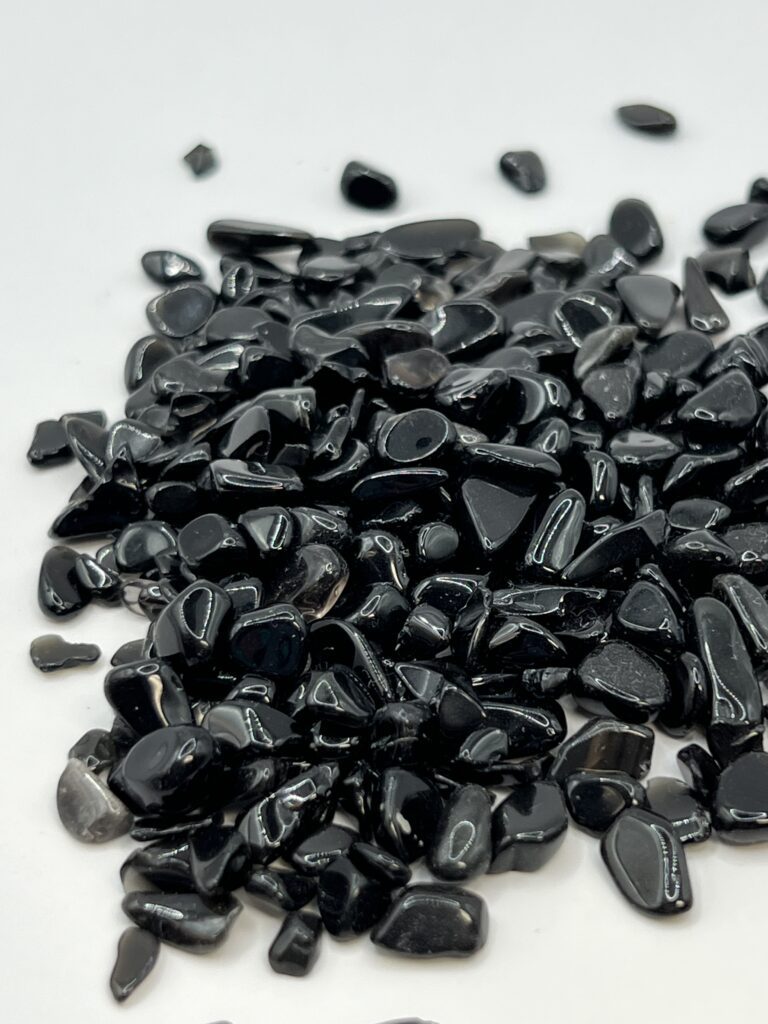 Black obsidian gemstone chips on white.