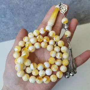 White and yellow prayer beads in hand.