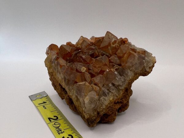 Orange quartz crystal cluster on rock.