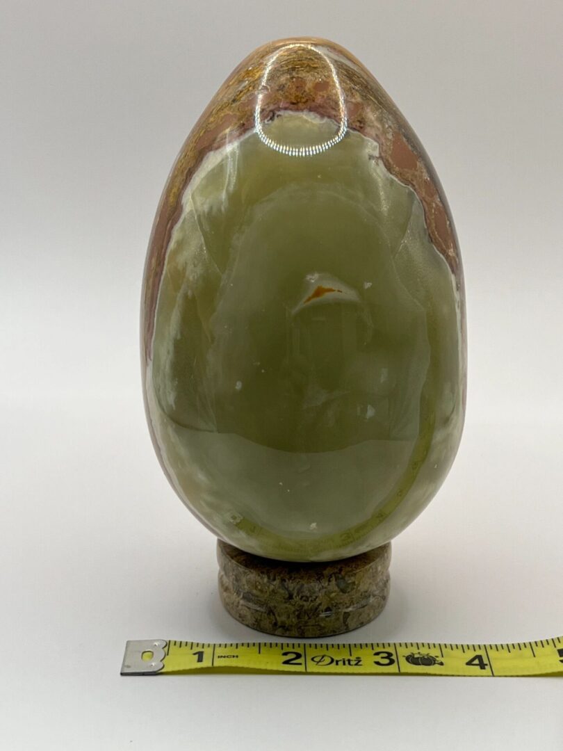 Green and brown marble egg on base.