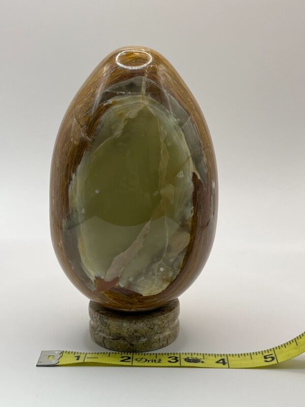 Green and brown marble egg on stand.