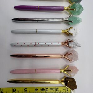 Seven crystal-topped pens on a white background.