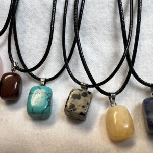 Six gemstone necklaces on black cords.