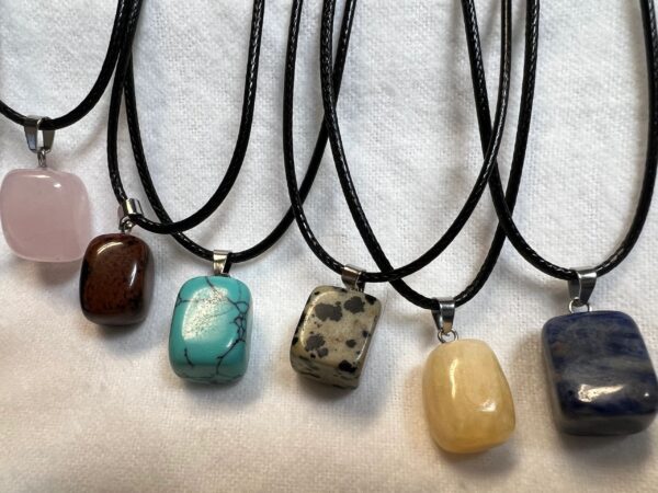 Six gemstone necklaces on black cords.