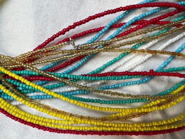 Multicolored beaded necklaces on white fabric.