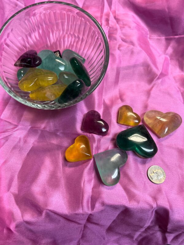 Colorful heart shaped crystal stones on pink fabric.