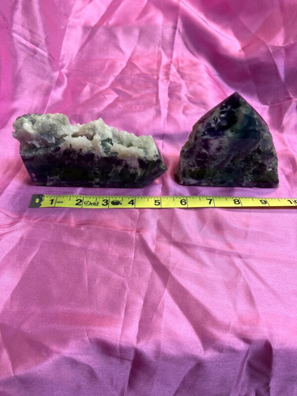 Two purple fluorite crystals on pink fabric.