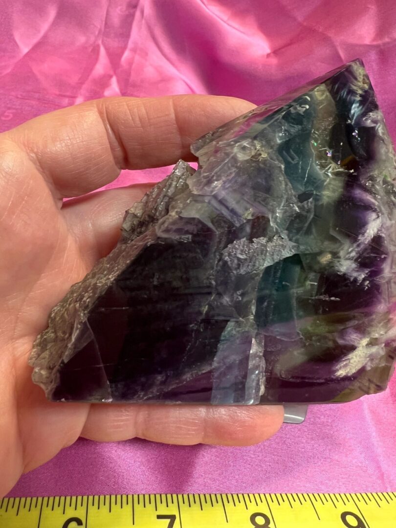 Hand holding a purple fluorite crystal.