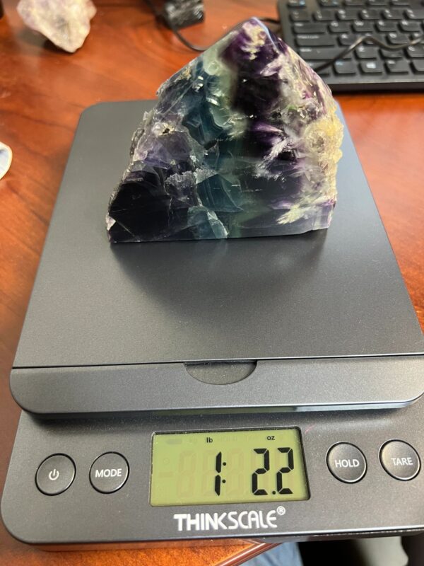 Green and purple fluorite crystal on a scale.