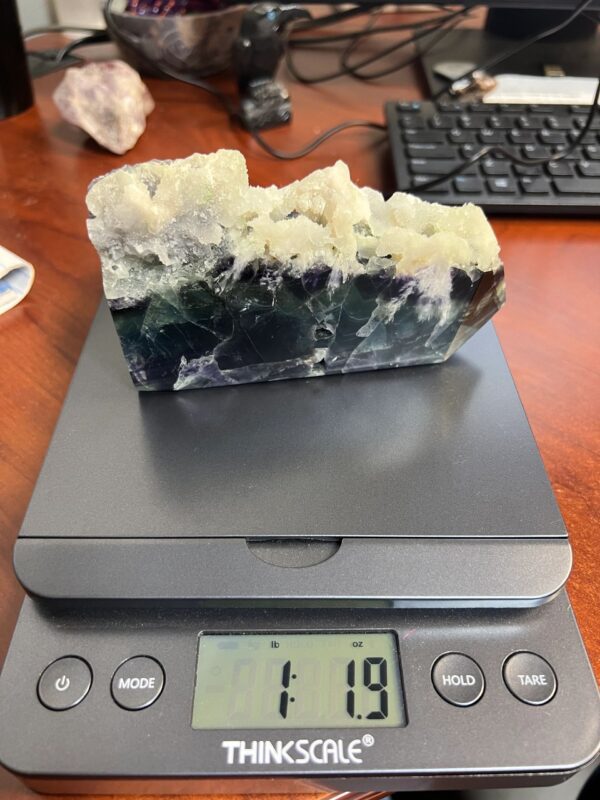 Green and purple fluorite crystal on scale.