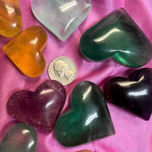 Colorful heart-shaped crystal stones on pink fabric.