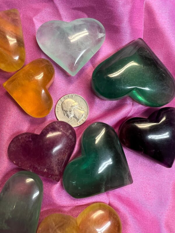 Colorful heart-shaped crystal stones on pink fabric.