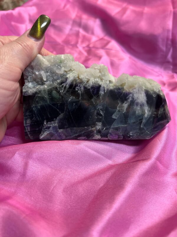 Purple and green fluorite crystal on pink fabric.