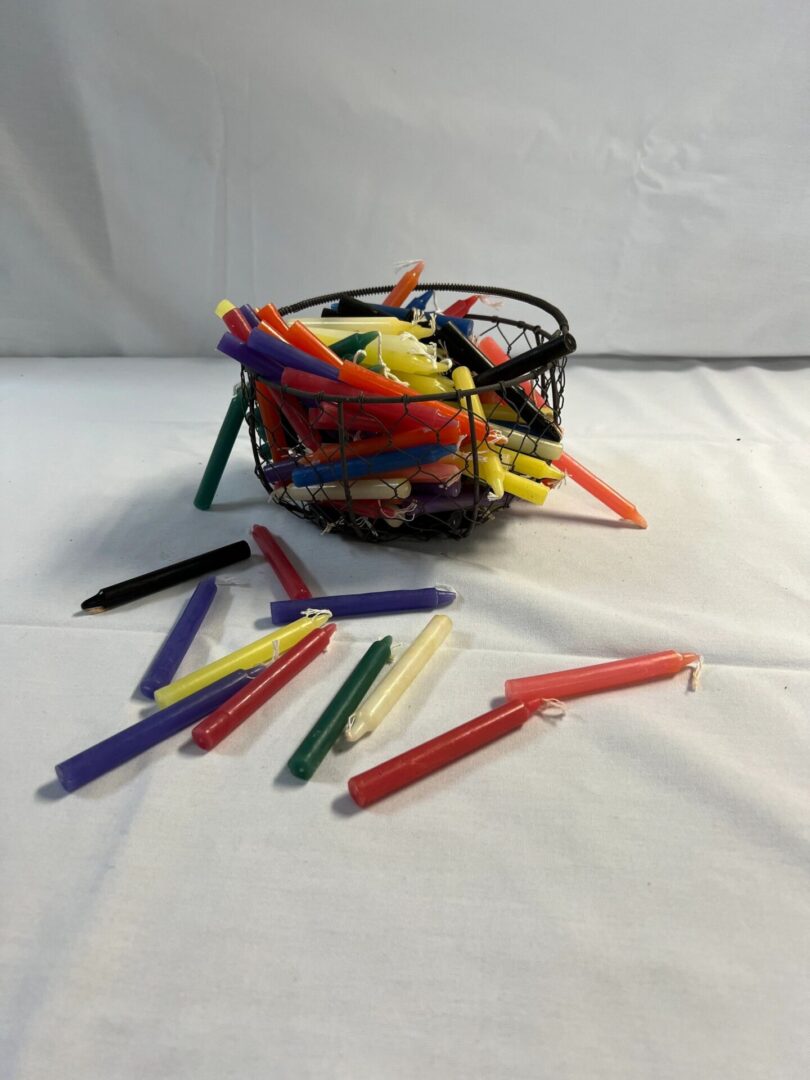 Multicolored candles in a wire basket.