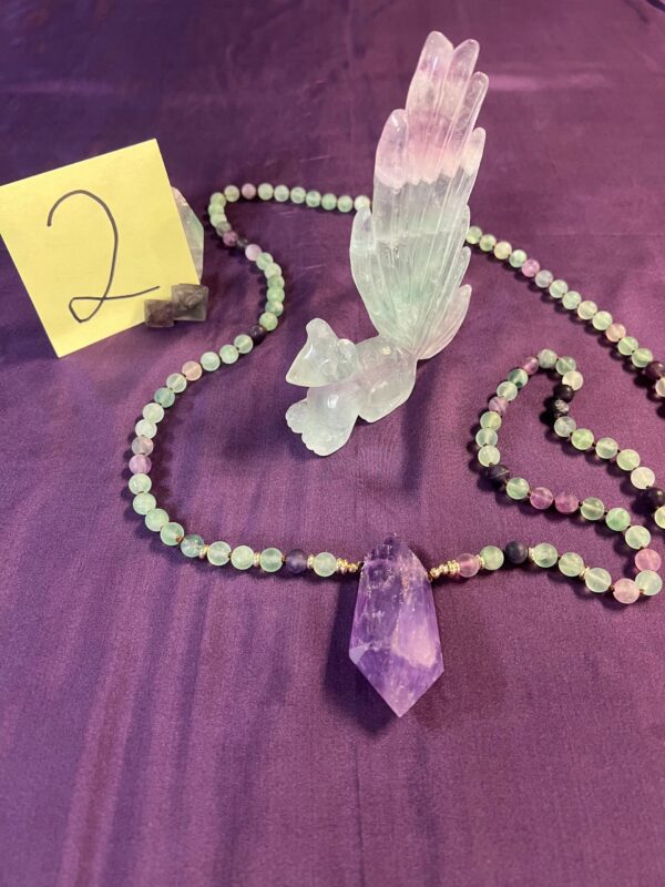 Amethyst crystal pendant with green beads.