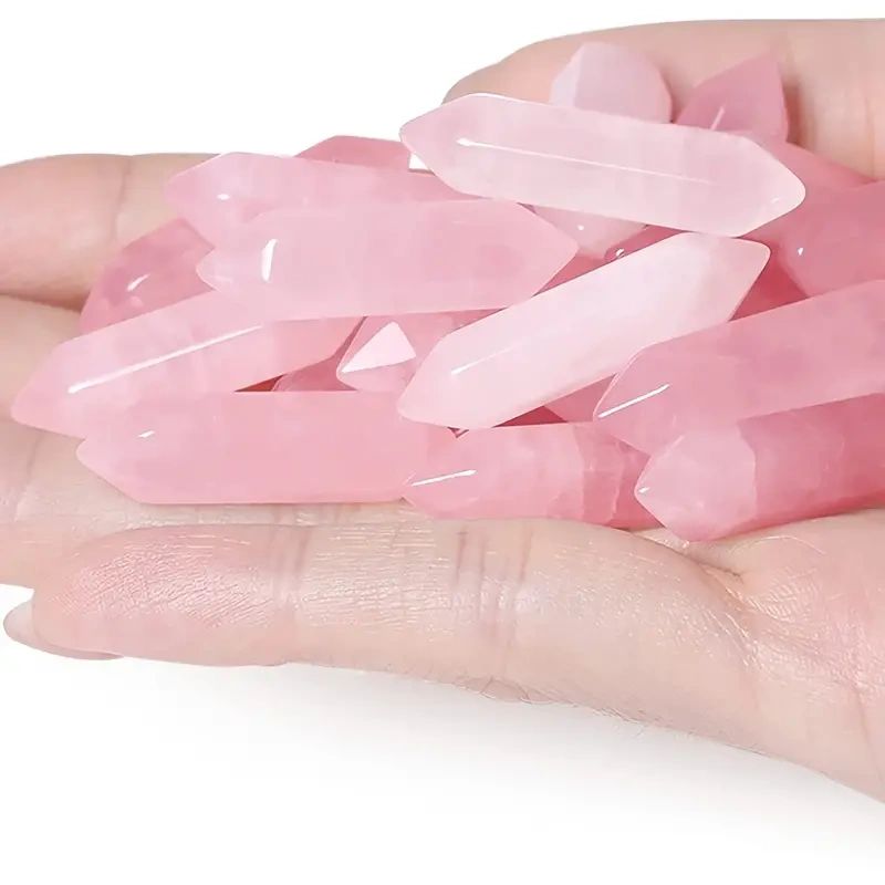 Pink rose quartz crystal points in hand.