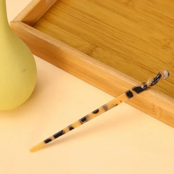 Tortoiseshell hair stick on wooden tray.