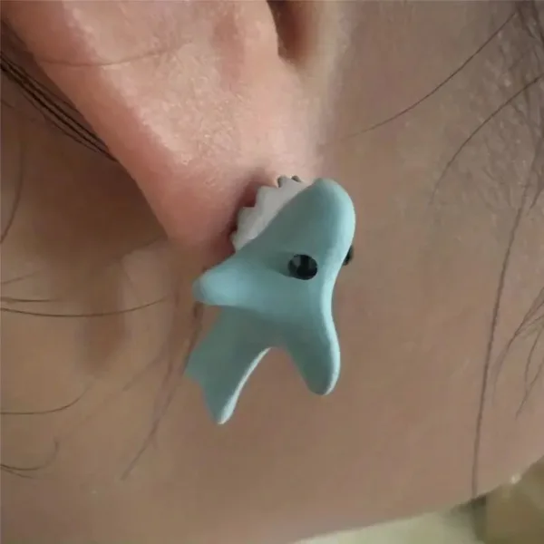 Blue shark earring on earlobe.