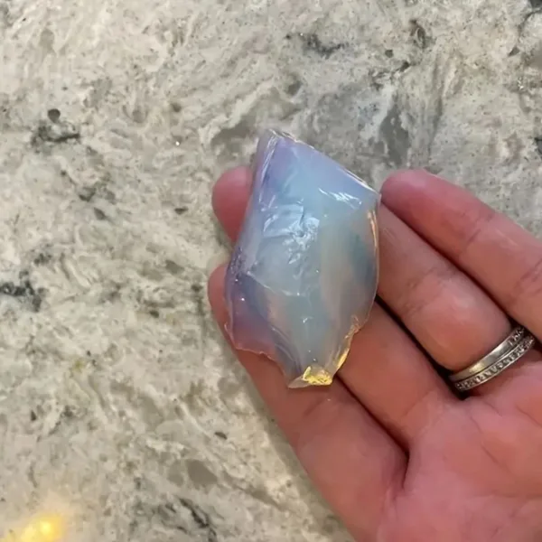 Irridescent opal stone in hand.