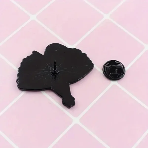 Black enamel ballerina pin on pink background.