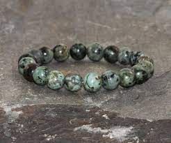 Green and black beaded bracelet on stone.