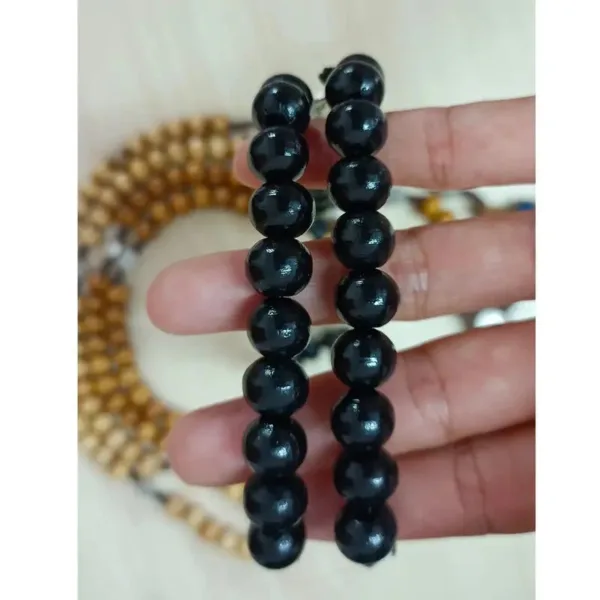 Two black beaded bracelets on hand.