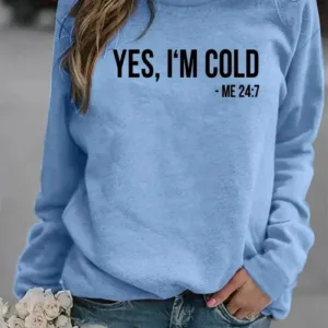 Woman wearing blue sweatshirt with "Yes, I'm cold" text.