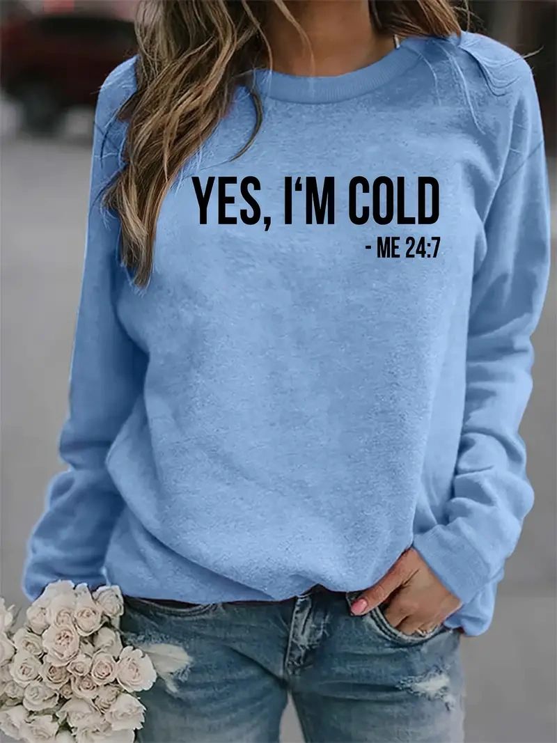 Woman wearing blue sweatshirt with "Yes, I'm cold" text.